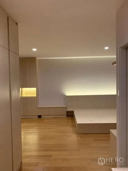 Townhouse for rent or sale in Saphan Sung, Bangkok - Master bedroom with platform bed base and indirect lighting against a wood accent wall.