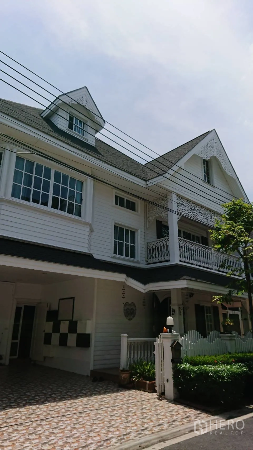 Detached House for rent in Mueang Samut Prakan, Samut Prakan - Exterior of a detached house with gabled roof, white facade, balcony and front garden.