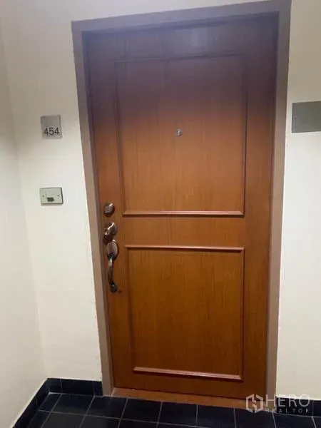 Condominium for sale in Watthana, Bangkok - Secure solid-wood condominium entrance door with unit number plaque in a clean corridor.