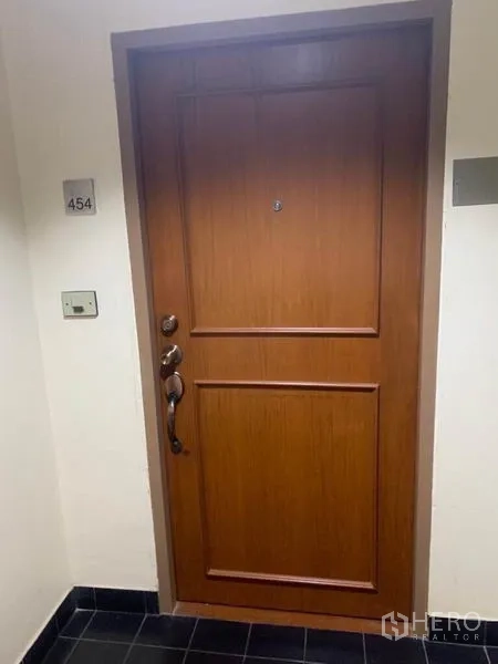 Condominium for sale in Watthana, Bangkok - Secure solid-wood condominium entrance door with unit number plaque in a clean corridor.
