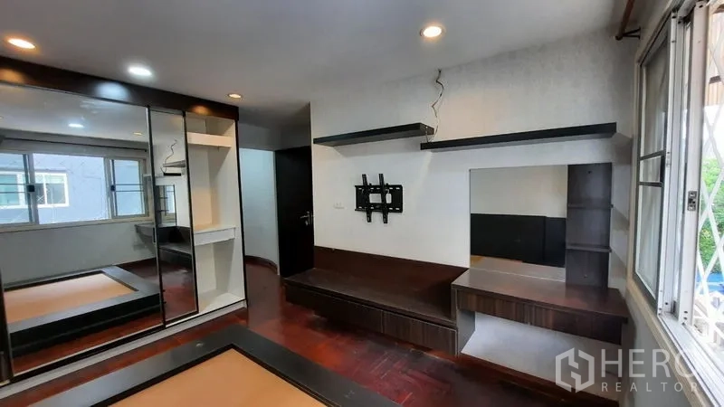 Townhouse for rent or sale in Suan Luang, Bangkok - Bedroom with mirrored wardrobe and built-in shelving units.