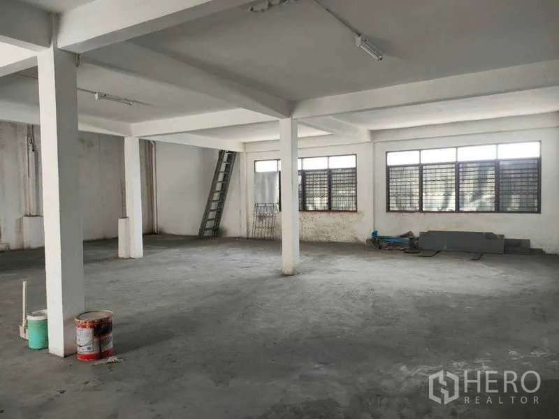 Shophouse for rent in Watthana, Bangkok - Bright open level with concrete floor, big windows and ladder access along the wall.