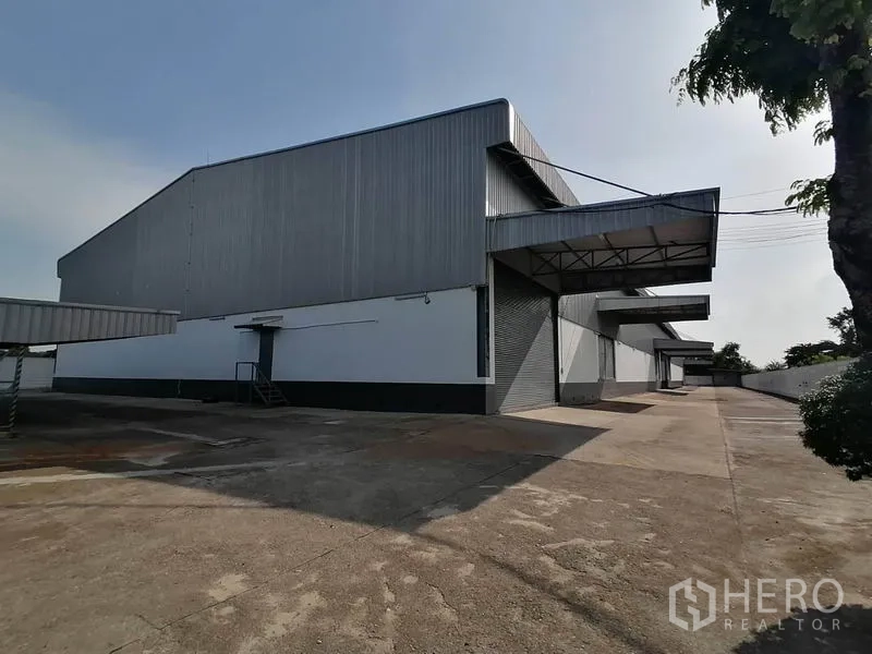 Warehouse for rent in Lat Krabang, Bangkok - Modern steel-clad warehouse exterior with multiple covered loading docks and a wide concrete yard in Lat Krabang.