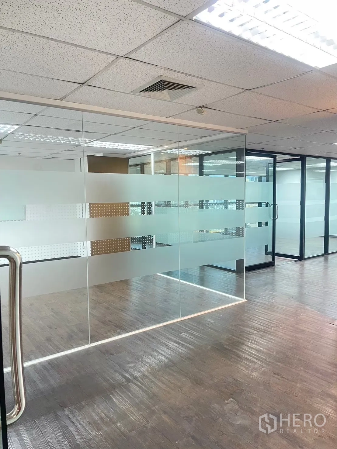 Office Space for rent in Watthana, Bangkok - Interior glass walls with frosted stripes next to dark wood floors and ceiling lights.