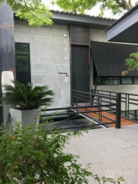 办公空间 出租在Bang Kapi, Bangkok - 中庭景观，玻璃立面建筑、连廊雨棚与院内停车位。