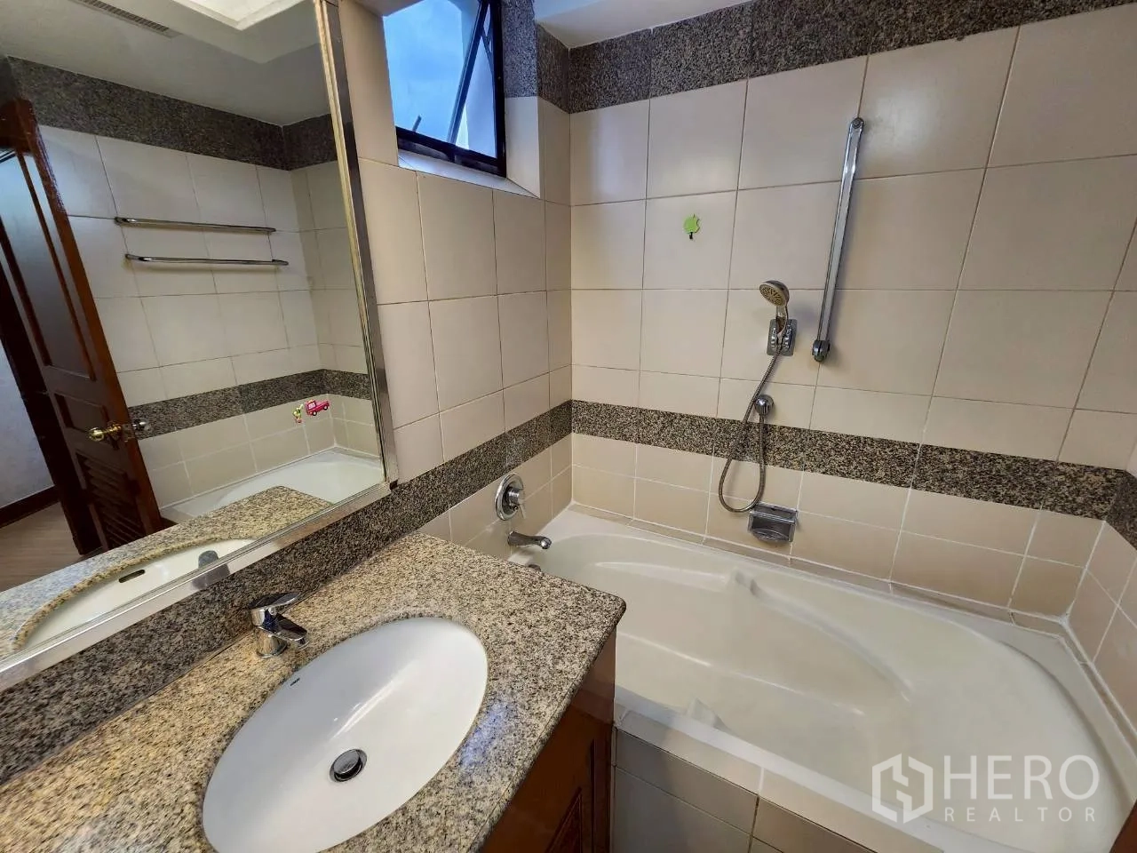 Condominium for rent in Khlong Toei, Bangkok - Bathroom with bathtub, granite vanity and large wall mirror.