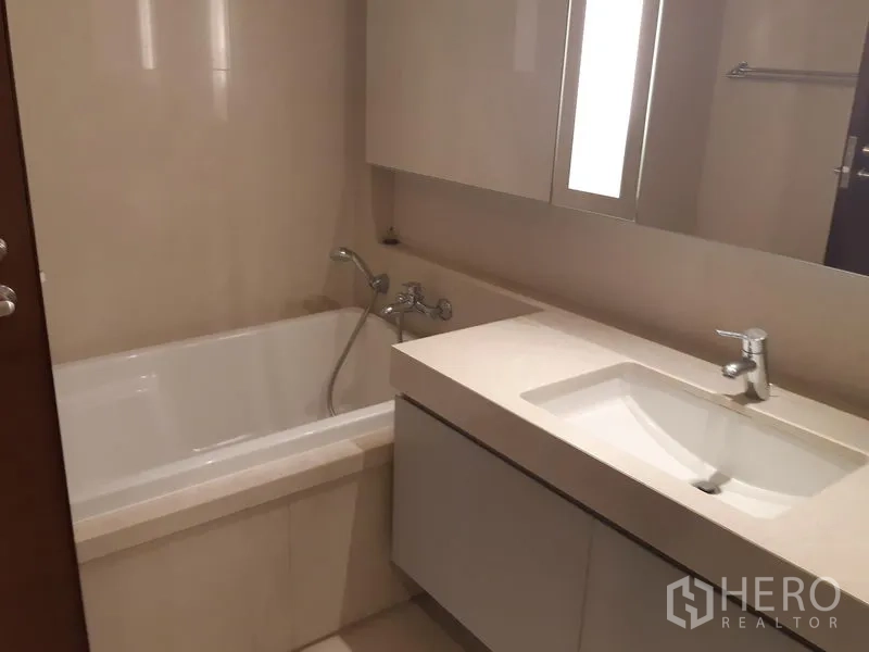 公寓 出租在Watthana, Bangkok - 浴室设内嵌浴缸、简洁洗手台与壁柜。