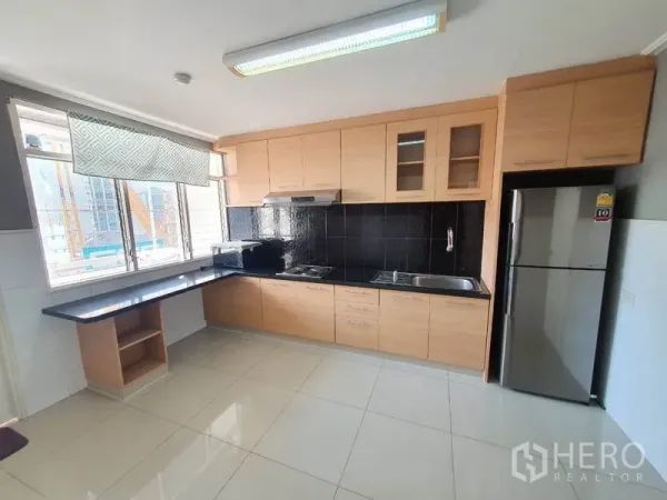 公寓 出租在Watthana, Bangkok - 独立厨房，浅木柜体、黑色挡板与大窗