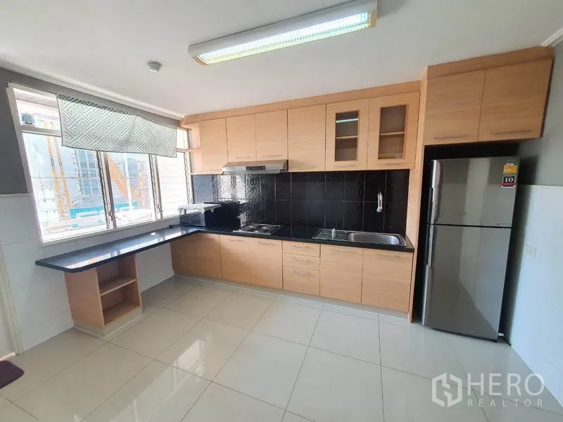 公寓 出租在Watthana, Bangkok - 独立厨房，浅木柜体、黑色挡板与大窗