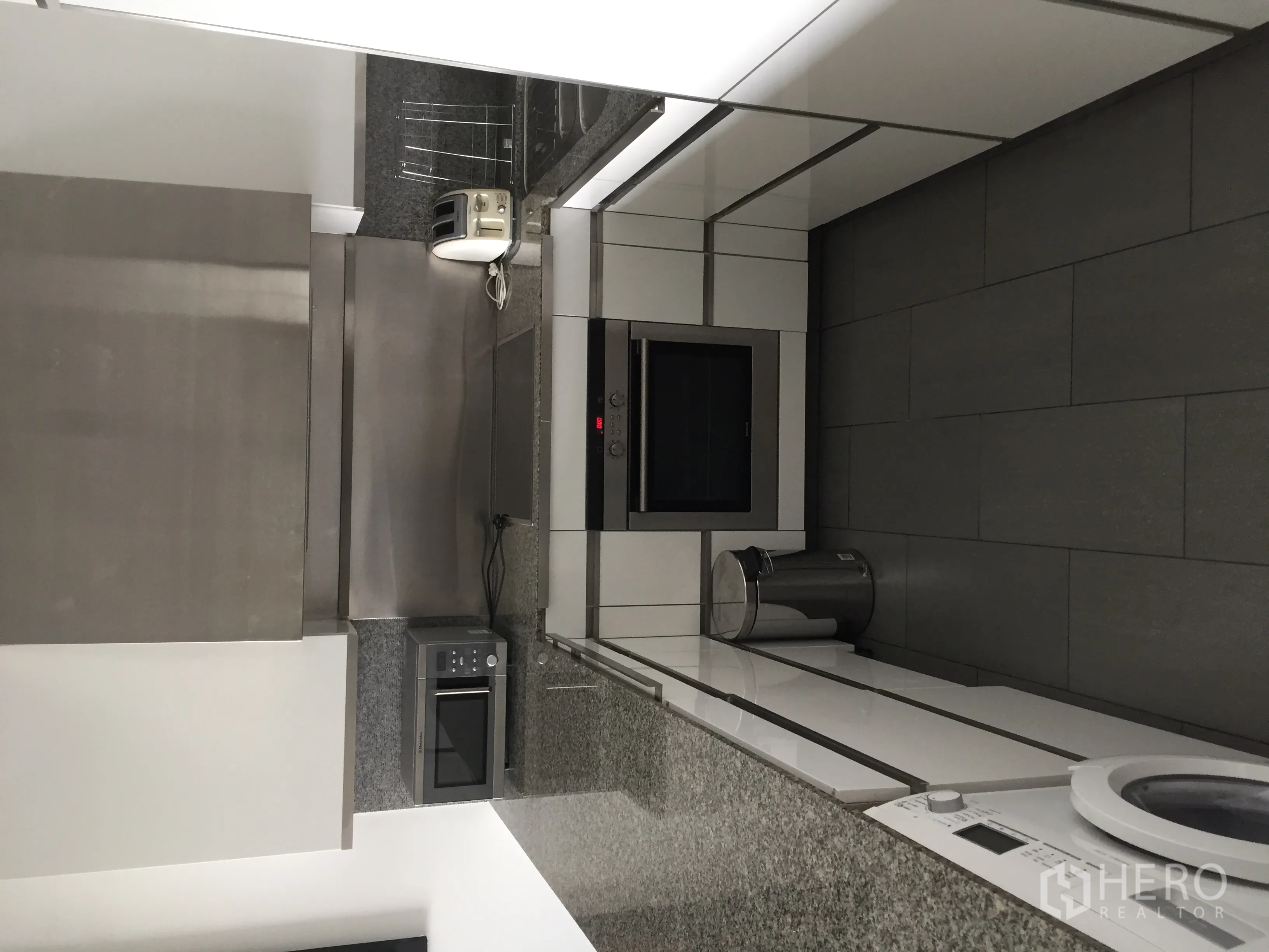 Condominium for rent in Sathon, Bangkok - Close-up of modern kitchen with granite countertops, built-in oven, and stainless appliances.