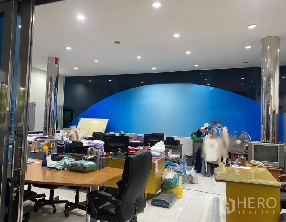 Factory for rent in Prawet, Bangkok - Glass-front office with desks, recessed lighting and a blue feature wall inside the factory.