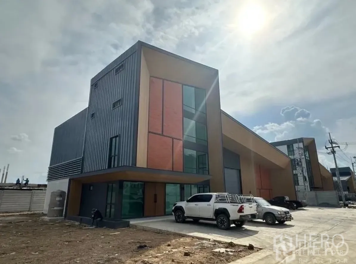 仓库 for sale in Lam Luk Ka, Pathum Thani - 现代仓库外观，金属板与砖饰立面，前方有停车位。