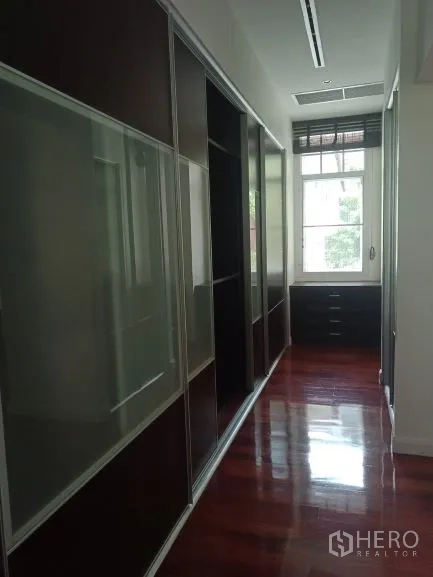 Detached House for rent in Bang Rak, Bangkok - Walk-in wardrobe corridor with built-in closets and a window for natural light.