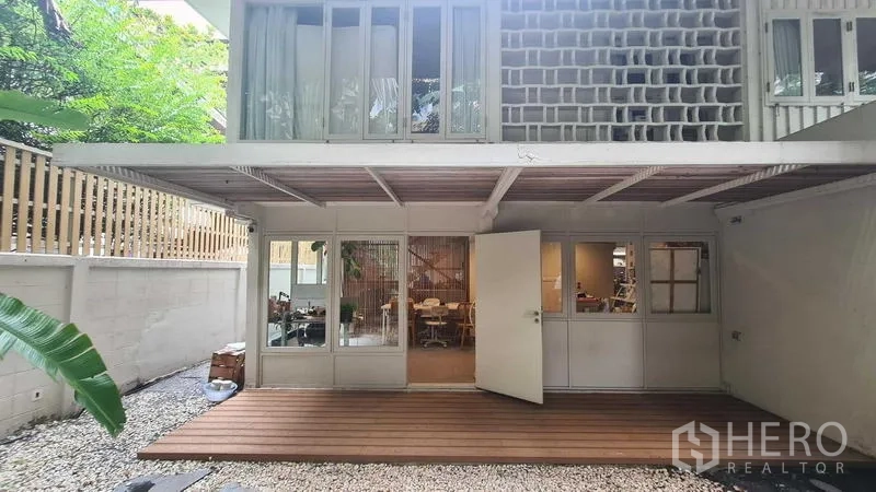 Detached House for rent in Watthana, Bangkok - Modern two-storey house with open glass doors and wooden deck patio.