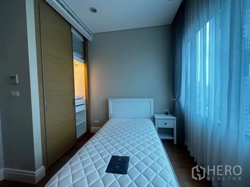 Condominium for rent in Khlong Toei, Bangkok - Single bedroom with sliding wardrobe, bedside table and expansive windows.