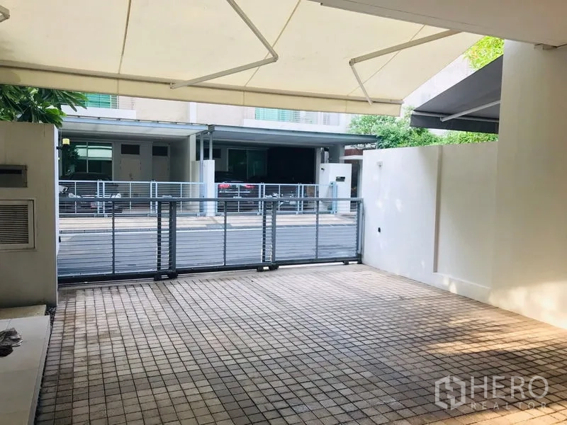 Townhouse for rent or sale in Chatuchak, Bangkok - Covered tiled carport with sliding metal gate offering secure parking.