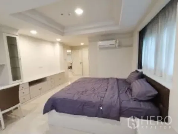 Apartment for rent in Watthana, Bangkok - Master bedroom featuring a king bed, built-in cabinets, work desk, air conditioner and window.