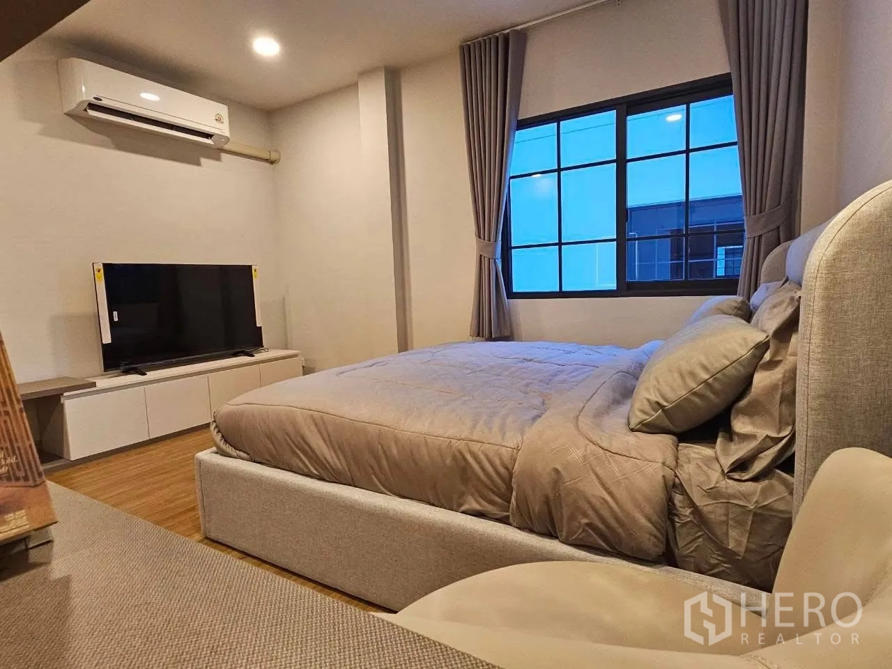 Detached House for rent or sale in Bang Phli, Samut Prakan - Cozy bedroom with upholstered bed, TV console, air conditioner, and curtained window.