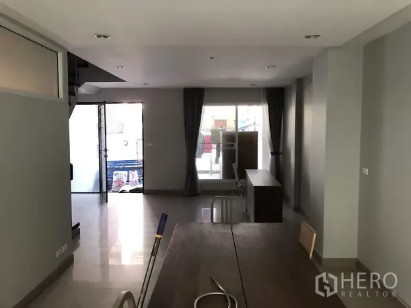 Townhouse for rent in Yan Nawa, Bangkok - Reverse view of the living–dining space with front and rear patios and full-height curtains.