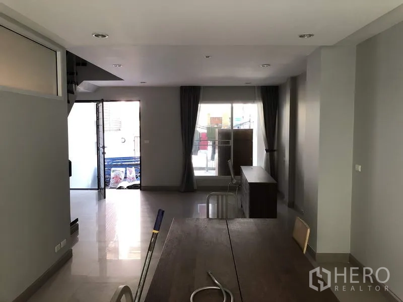 Townhouse for rent in Yan Nawa, Bangkok - Reverse view of the living–dining space with front and rear patios and full-height curtains.