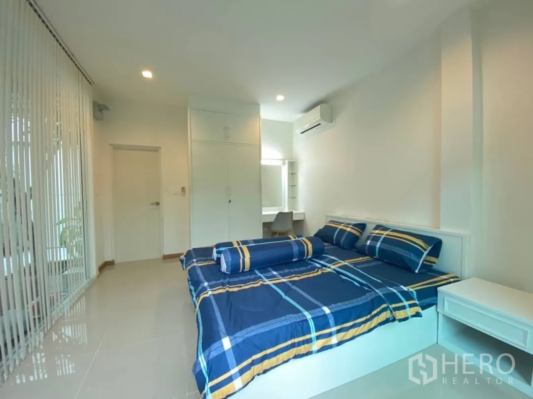 Detached House for rent or sale in Prawet, Bangkok - Guest bedroom with blue bedding, study desk and built-in wardrobe.