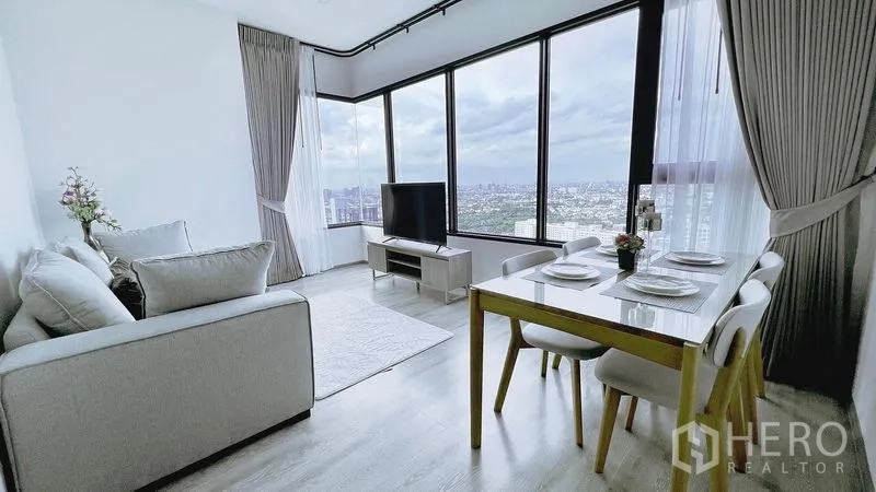 公寓 出租在Watthana, Bangkok - 采光充足的转角客餐厅，落地窗、电视柜与曼谷天际线景观。