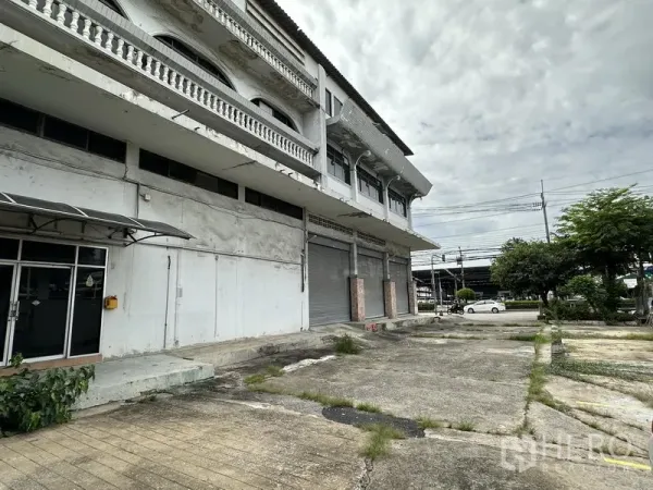 Home Office for rent in Khan Na Yao, Bangkok - Side facade showing balcony details and a broad forecourt for parking in front of the building.