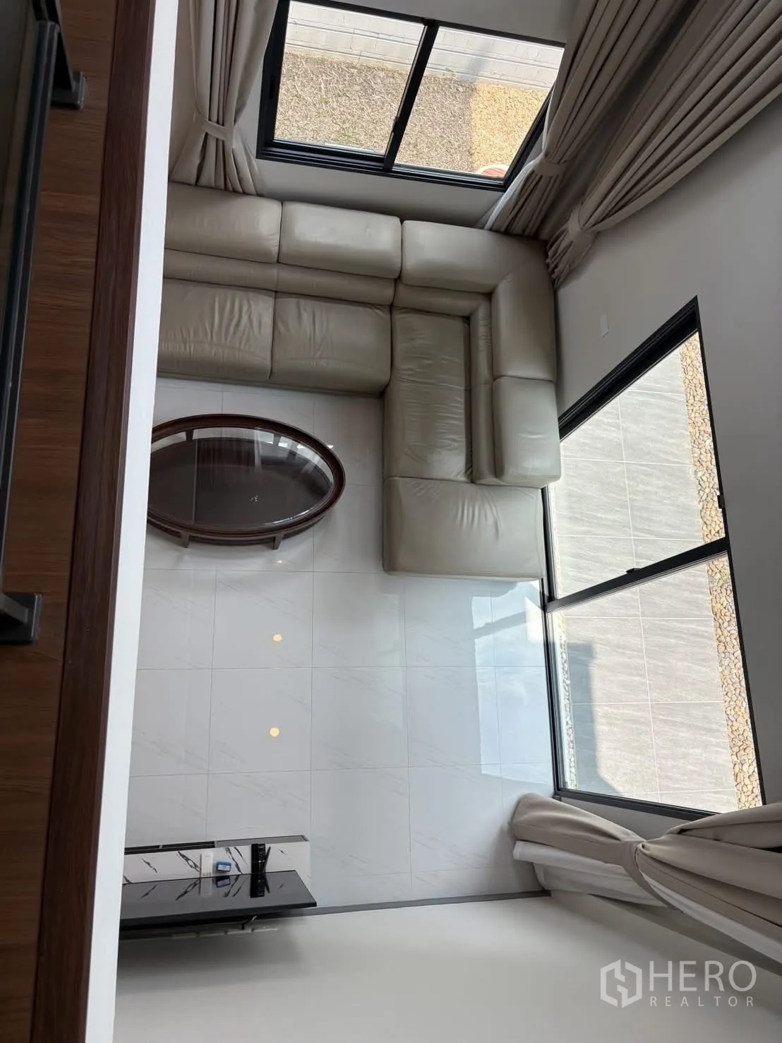 Townhouse for rent - Aerial view from the mezzanine of the living room with cream leather sofa and oval glass table.