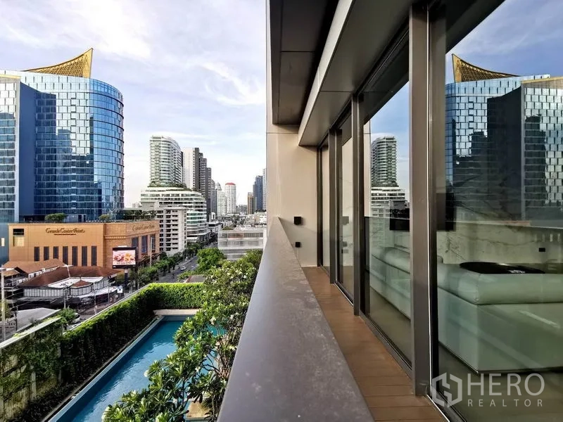 公寓 出租或出售在Watthana, Bangkok - 阳台城市景观，可俯瞰泳池与通罗天际线的玻璃建筑。