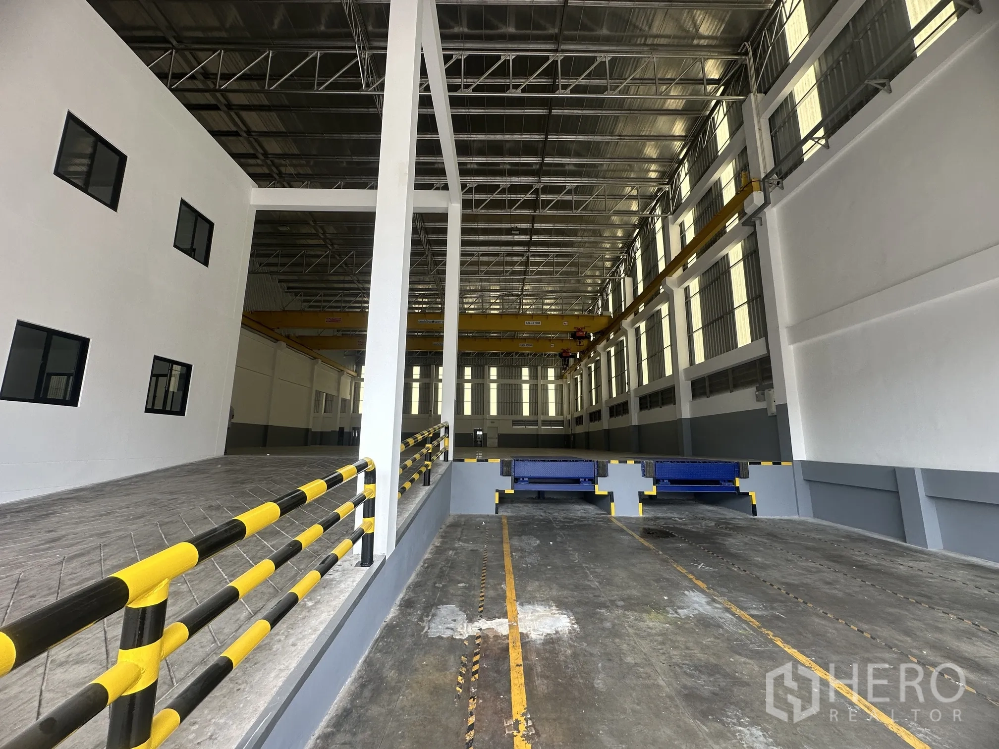 Factory for rent in Bang Phli, Samut Prakan - Interior loading area with two dock levelers, ramp, and adjacent office block.