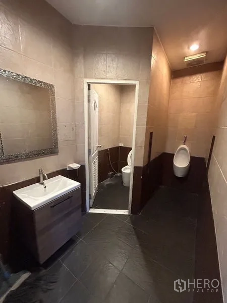 Retail Space for rent - Restroom featuring sink, mirror, urinal and separate toilet cubicle.