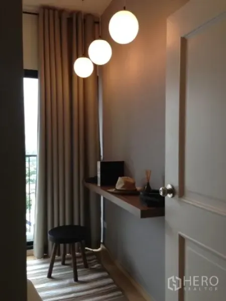 Condominium for rent in Phaya Thai, Bangkok - Compact work area by the balcony with a floating wooden desk, stool and three globe pendant lights.