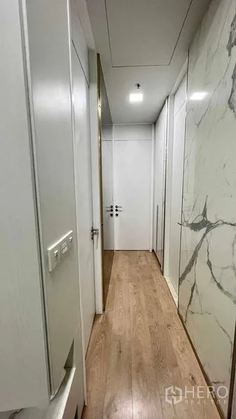 Condominium for rent in Watthana, Bangkok - Narrow corridor lined with marble feature wall and storage.