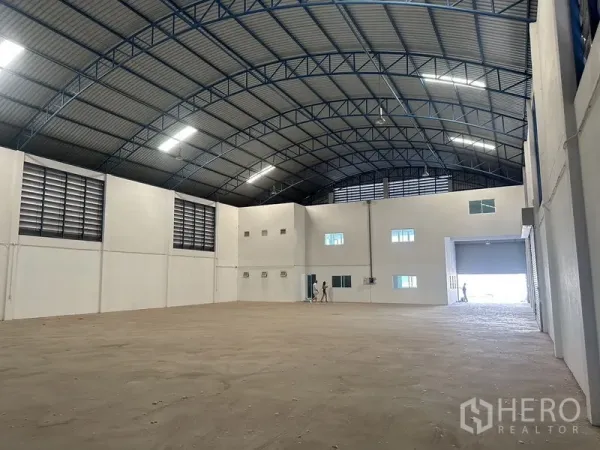 Factory for rent in Bang Bo, Samut Prakan - Open warehouse floor with arched steel truss roof, wall ventilation louvers and bright lighting.