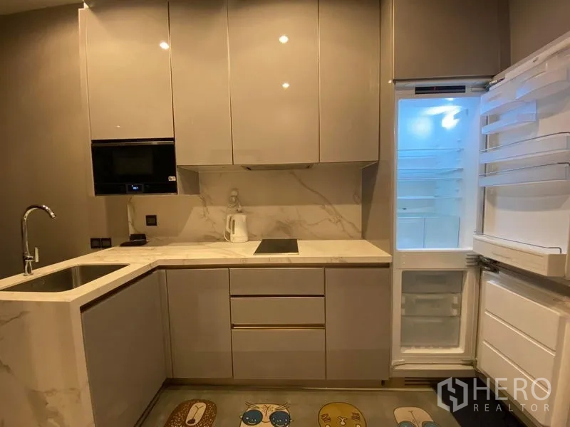 公寓 出租在Huai Khwang, Bangkok - 光泽面L形厨房，配感应炉、嵌入式微波炉和打开的冰箱。