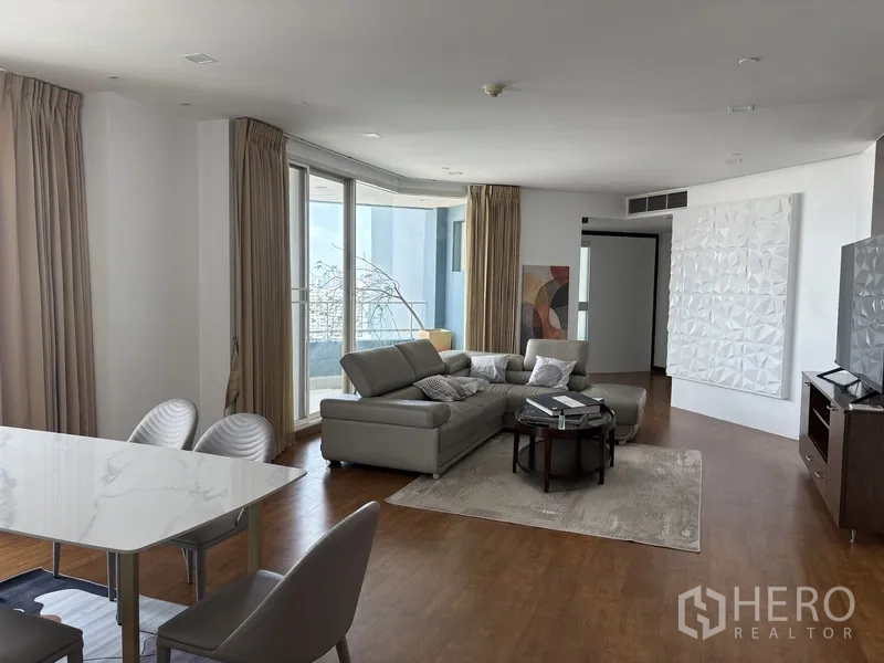 公寓 for rent in Khlong San, Bangkok - 明亮客厅，L形皮沙发、地毯与大面积玻璃门。