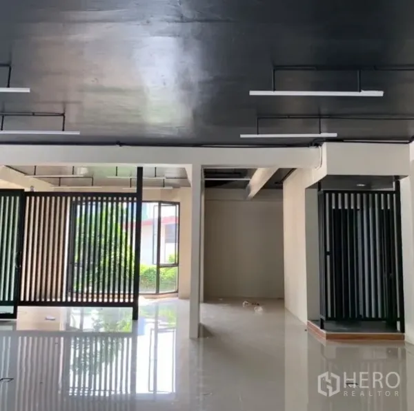 Standalone for rent in Khlong Toei, Bangkok - Open-plan ground floor with black ceiling, linear lights, and glass-slatted partitions offering flexible layout.
