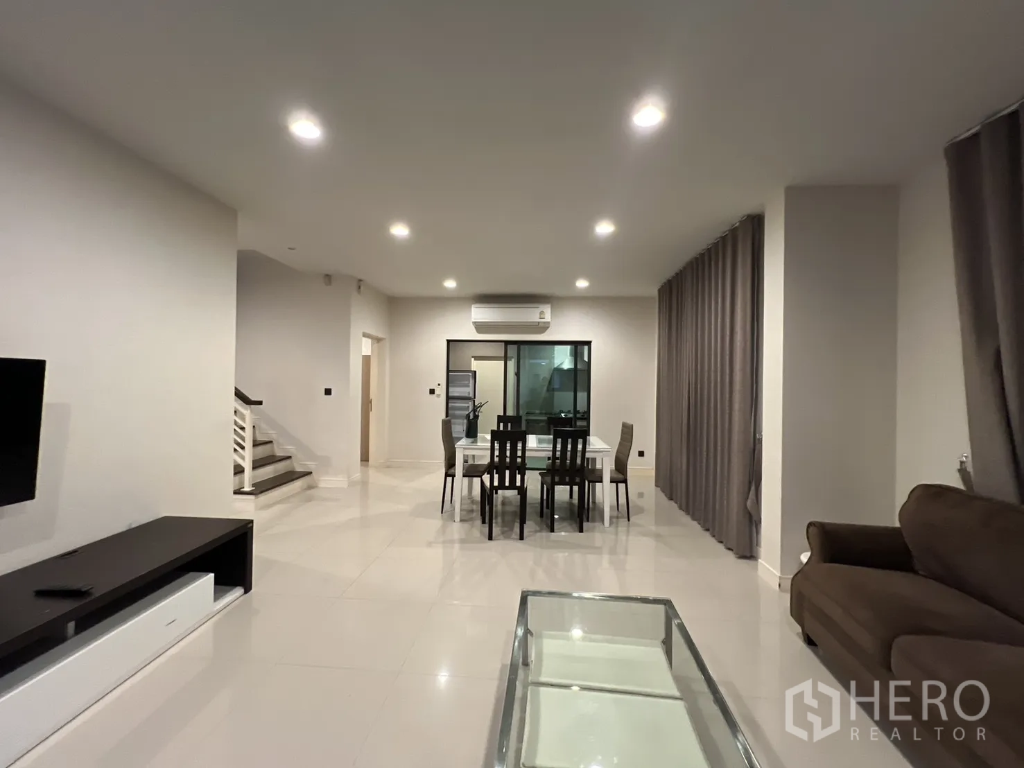 Detached House for rent or sale in Bang Kapi, Bangkok - Living area with wall-mounted TV opposite a dining table.