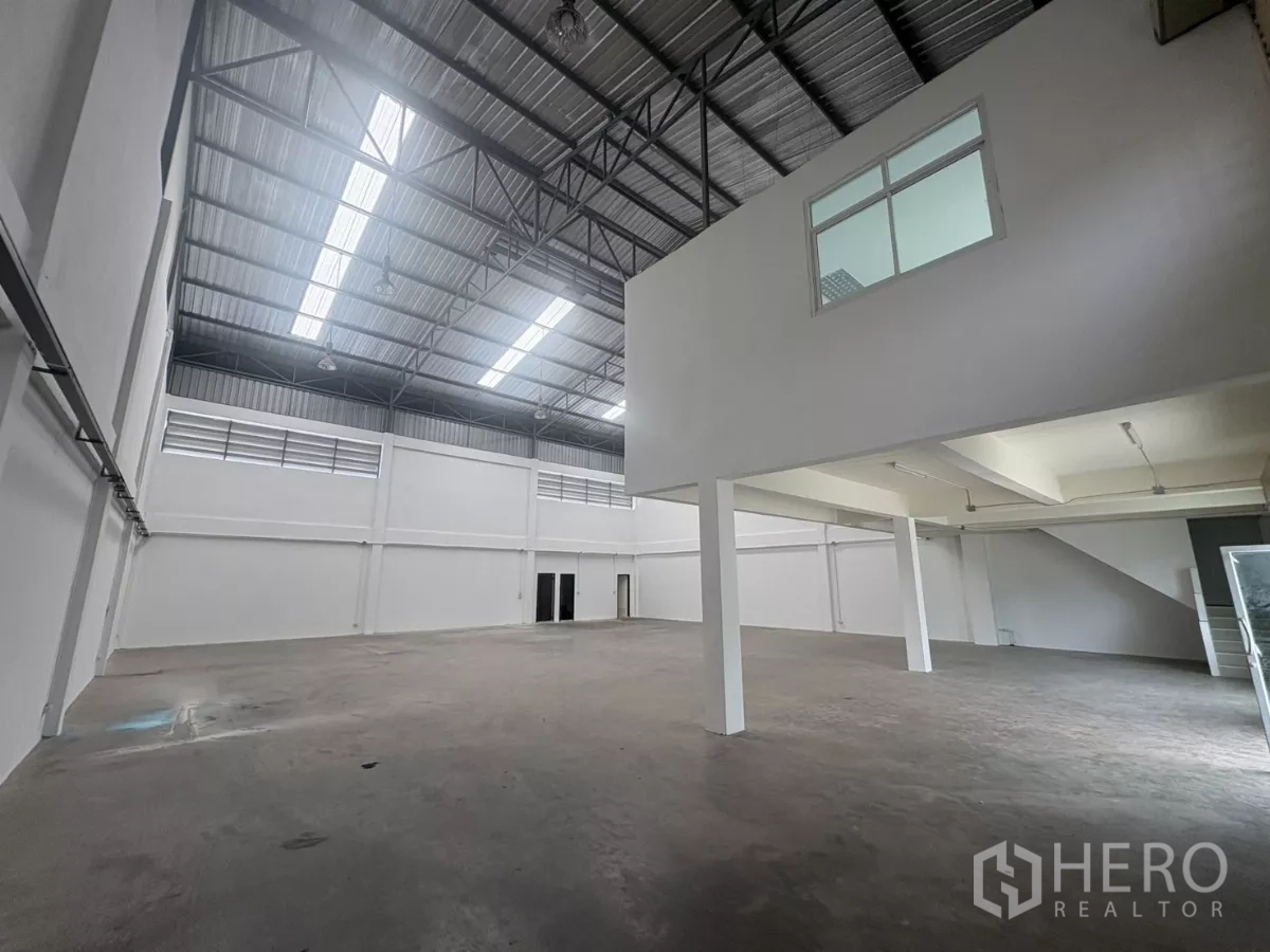 Factory for rent in Phra Samut Chedi, Samut Prakan - Spacious warehouse interior with high steel roof, skylights and a mezzanine office block.