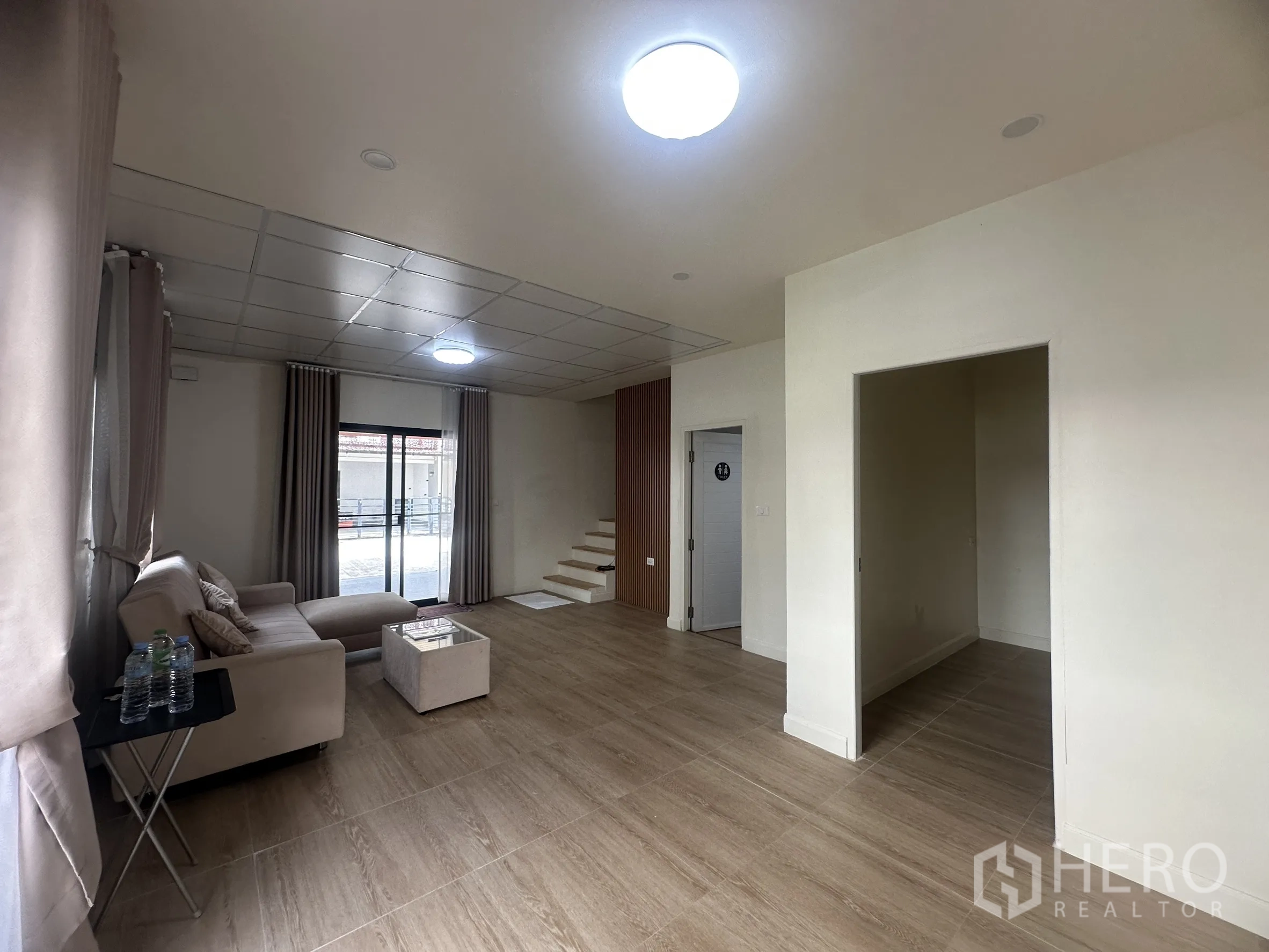 Townhouse for sale in Lam Luk Ka, Pathum Thani - Living room with recessed lighting and an under-stair storage niche.