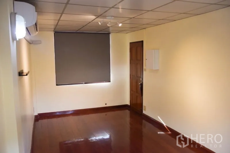Townhouse for rent in Watthana, Bangkok - Upper-floor room with wood flooring, window shade and air conditioner.