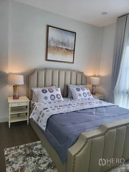Detached House for rent in Saphan Sung, Bangkok - Bright bedroom with tufted headboard, bedside tables and a large window.