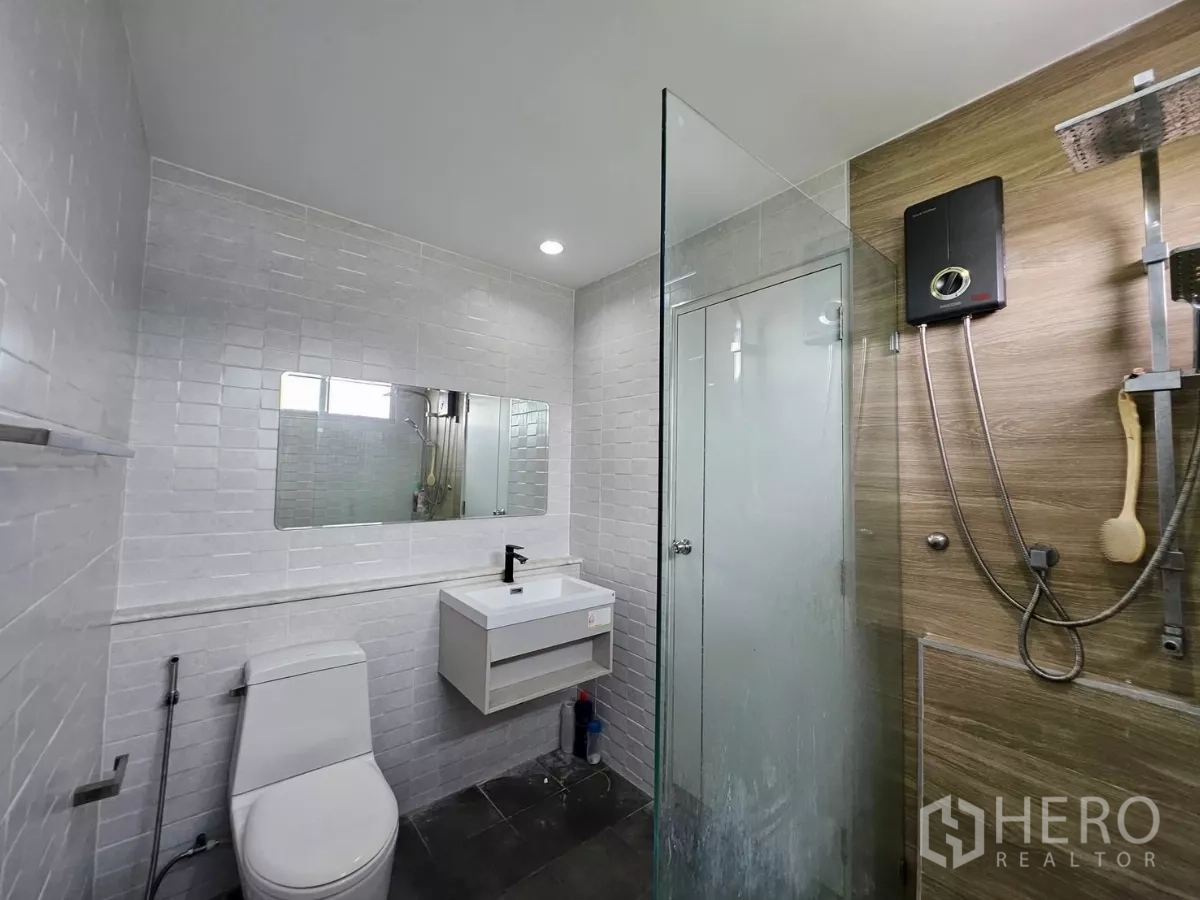 Detached House for rent in Khlong Toei, Bangkok - Renovated bathroom with glass shower, rain shower head, white subway tiles and vanity.