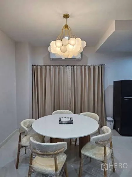 Townhouse for rent in Suan Luang, Bangkok - Close-up of dining corner with round table, modern pendant light and curtains.