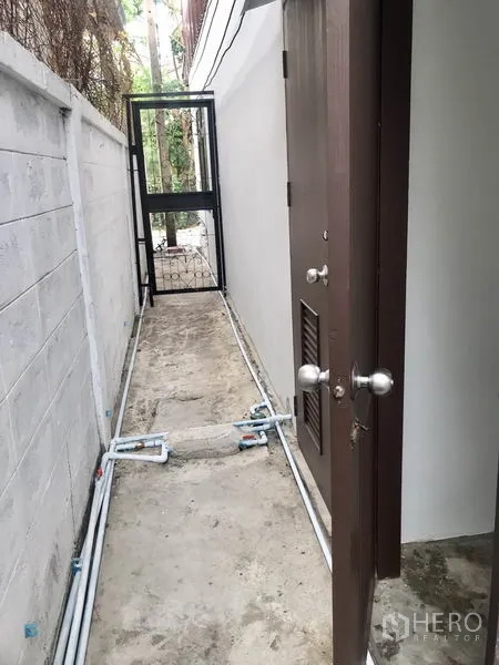 货栈 出租在Pathum Thani - 侧边通道，设服务门、混凝土走道与金属小门。