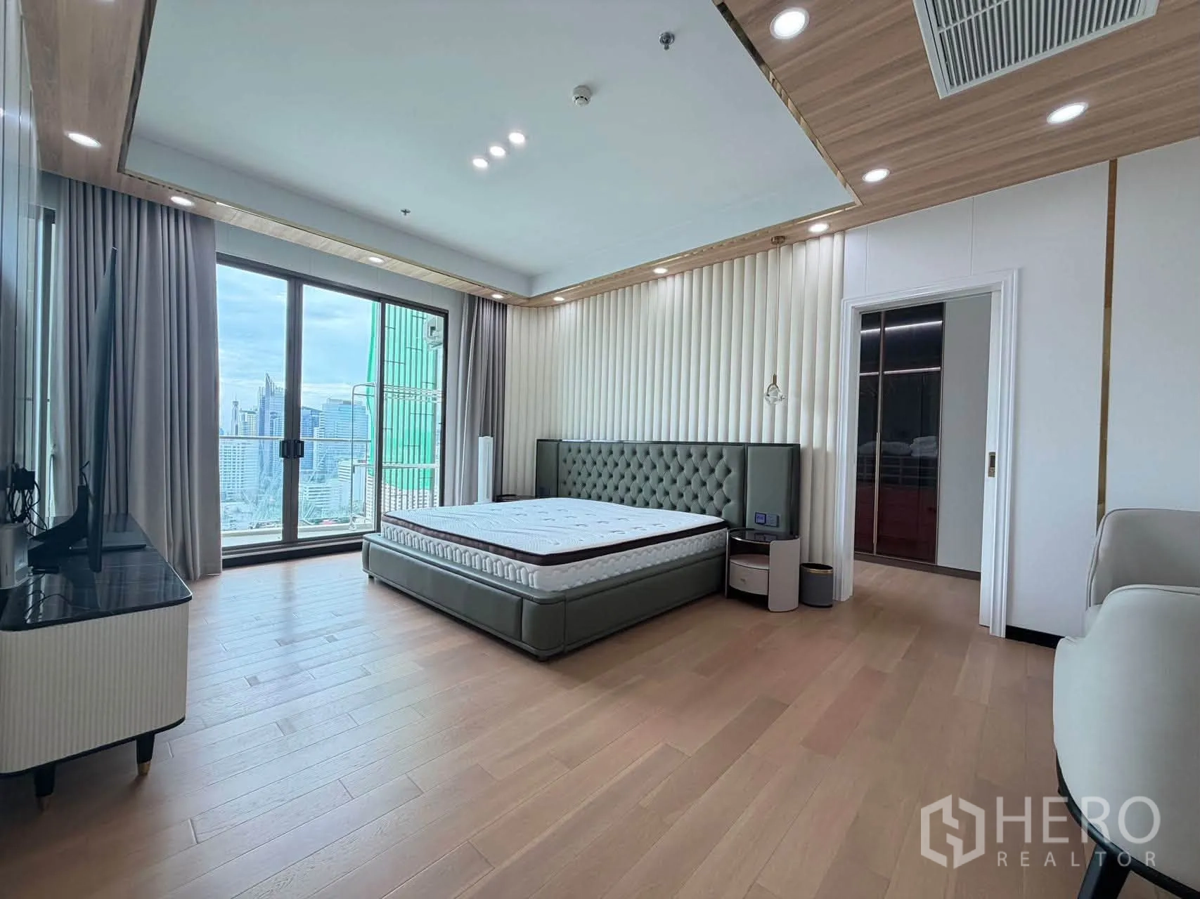 Condominium for sale in Watthana, Bangkok - Spacious bedroom with sliding glass door to city outlook and wood floors.