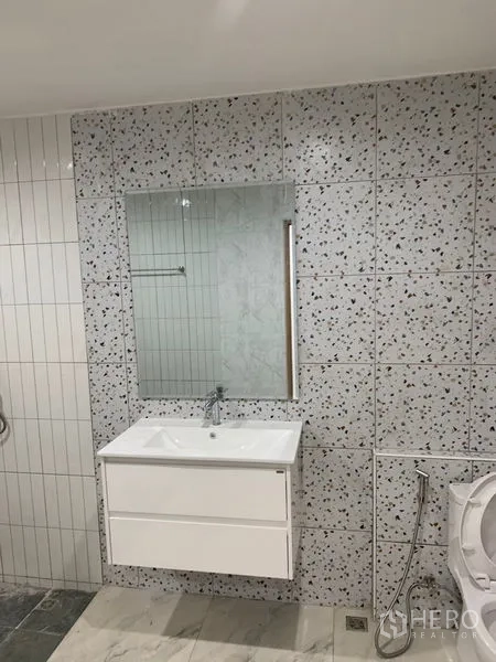 Townhouse for sale in Yan Nawa, Bangkok - Modern bathroom with terrazzo wall tiles, mirror, and floating vanity.