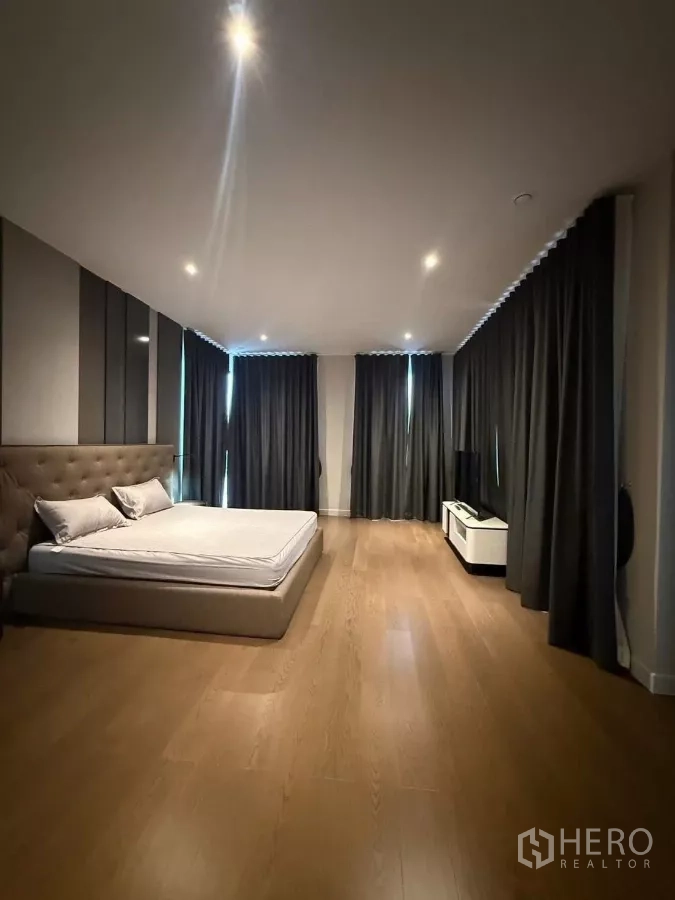 Detached House for rent in Saphan Sung, Bangkok - Large bedroom with corner windows, dark curtains and media console on wood floors.