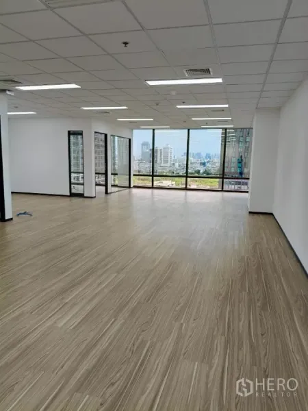 Office Space for rent - Bright open-plan office with wood-look flooring, grid ceiling lights and full-height windows overlooking the Bangkok skyline.