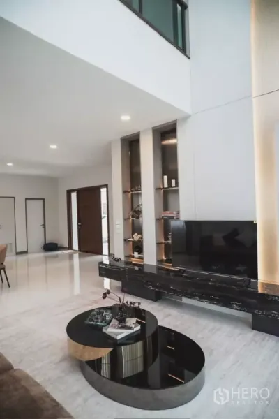 独立式住宅 出租在Bang Phli, Samut Prakan - 开放式客厅，双层挑高天花，悬浮电视柜与圆形套叠茶几。
